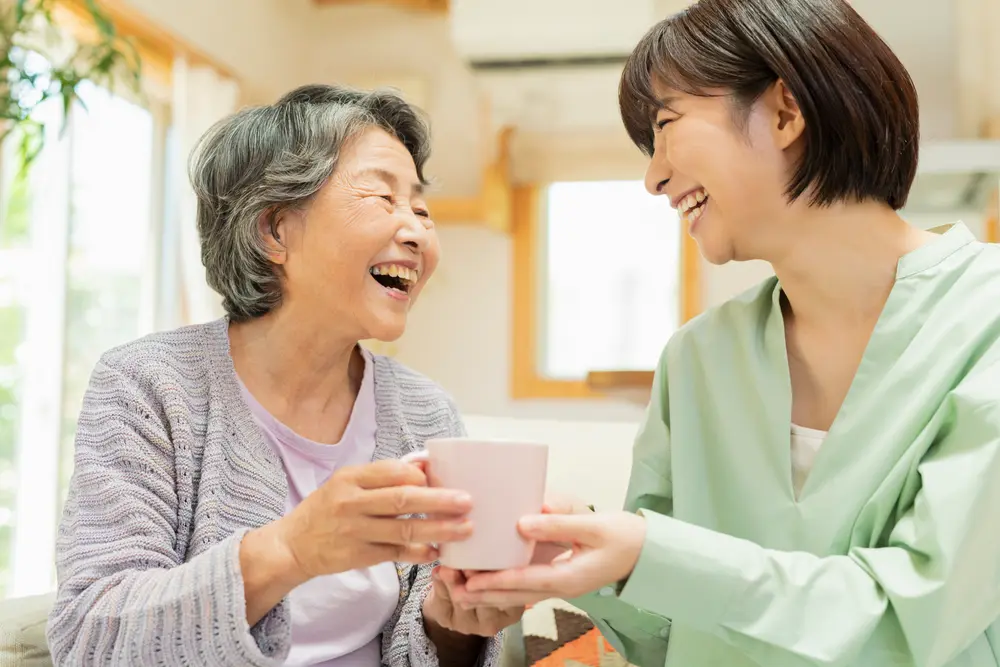 お茶を飲みながら笑い合う高齢女性とスタッフ