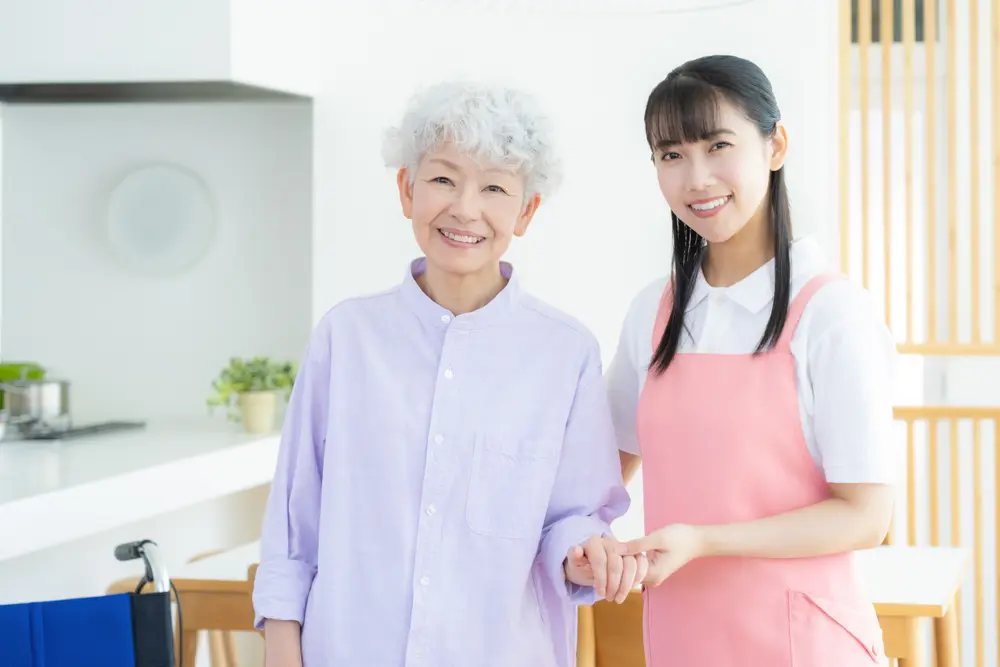 高齢女性の手を取る若い介護スタッフ