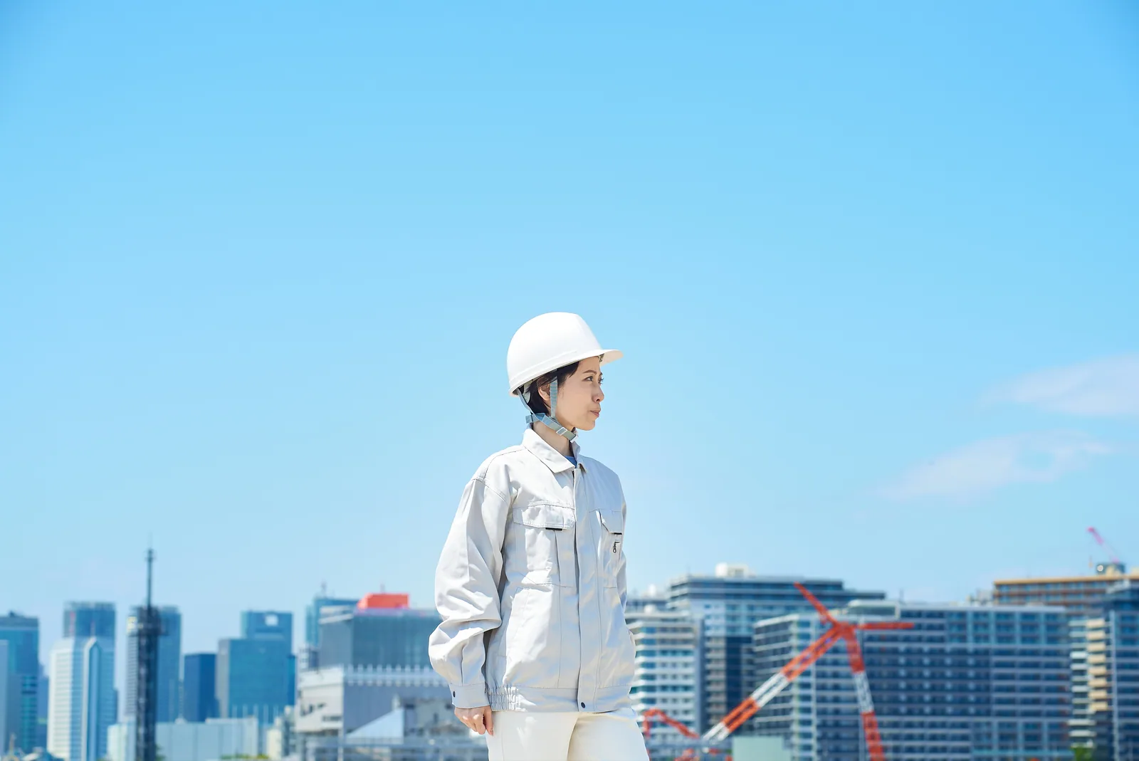 市街地を背景に立つ建設作業員