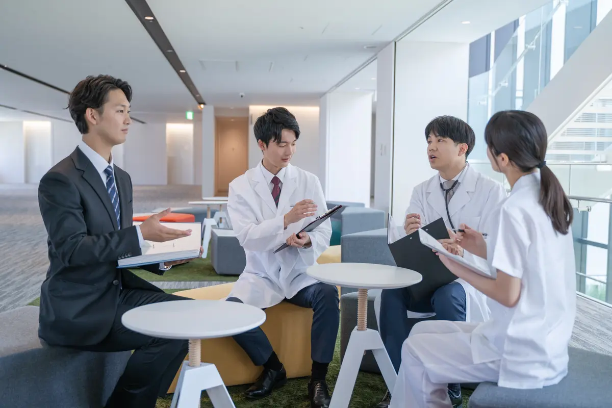 スーツ姿と白衣姿が同席する打ち合わせ
