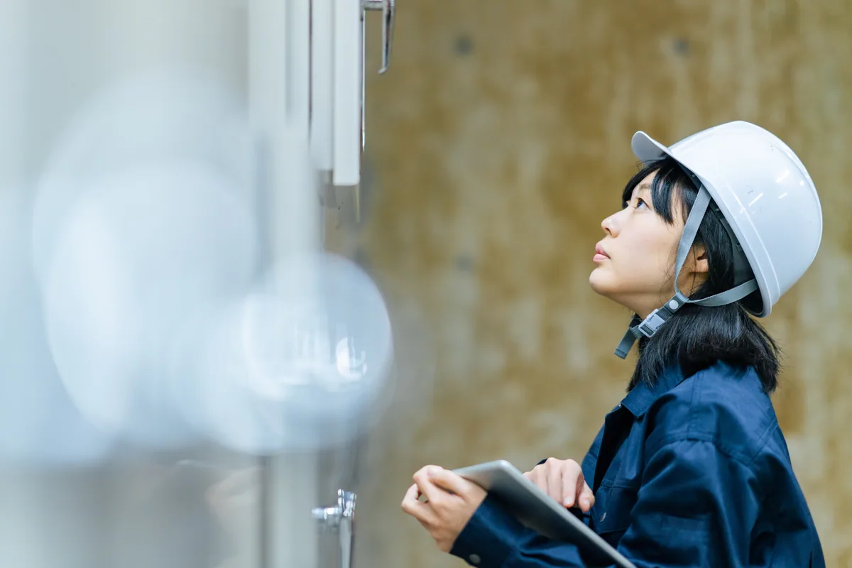 装置を見上げる若手の女性エンジニア
