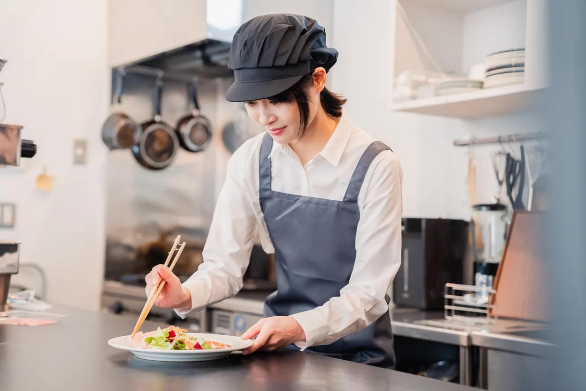 厨房で料理を盛り付ける女性スタッフ