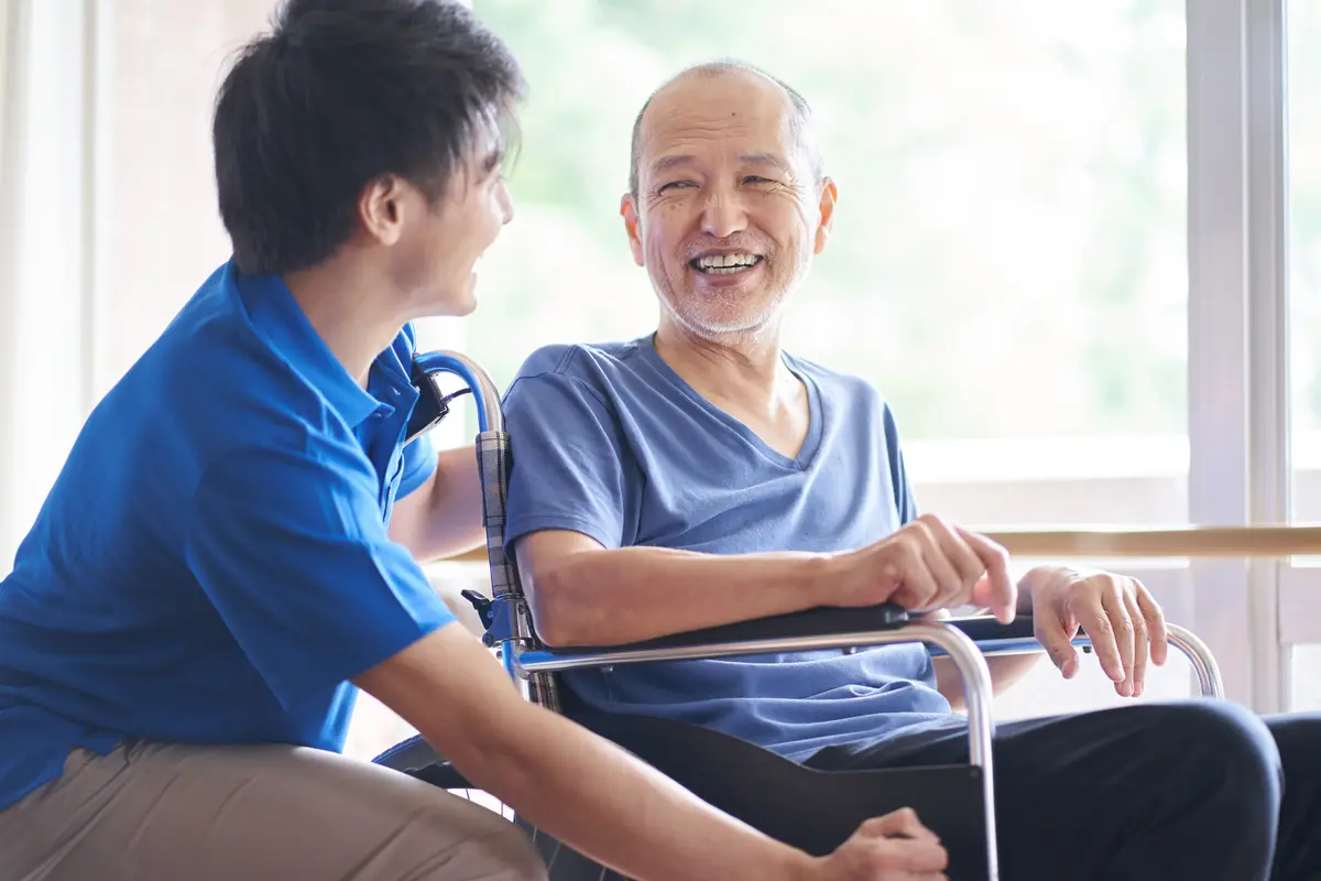 椅子に座る高齢の男性とかがんで話すスタッフ